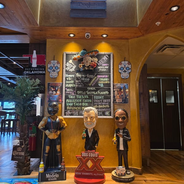 Mexican restaurant interior featuring Dos Equis, Modelo, and Corona displays, colorful sugar-skull decorations, and a chalkboard of specials.