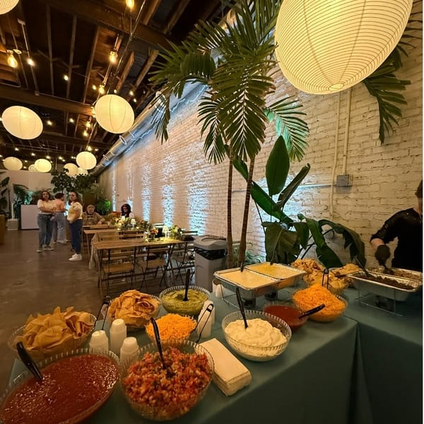 Mexican food buffet with chips, salsa, guacamole, and cheese in a festive restaurant setting.