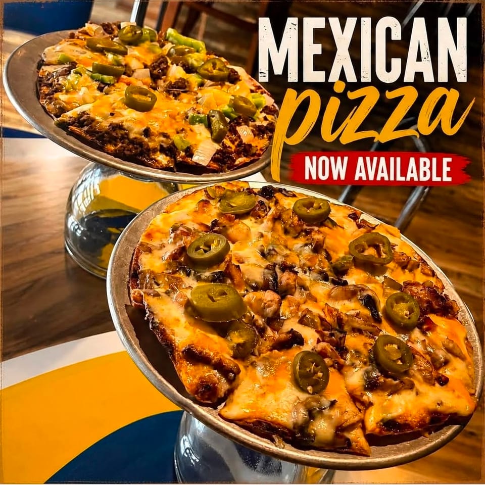 Two cheesy Mexican pizzas topped with jalapeños, beans, peppers, onions, and meat, displayed on raised metal serving stands.